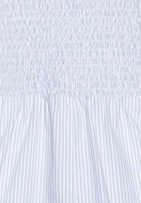 Himmelblau und weiß gestreifter Stoff mit gerüschtem Smocking oben, der in einen volleren Rock mit weicher Textur übergeht.