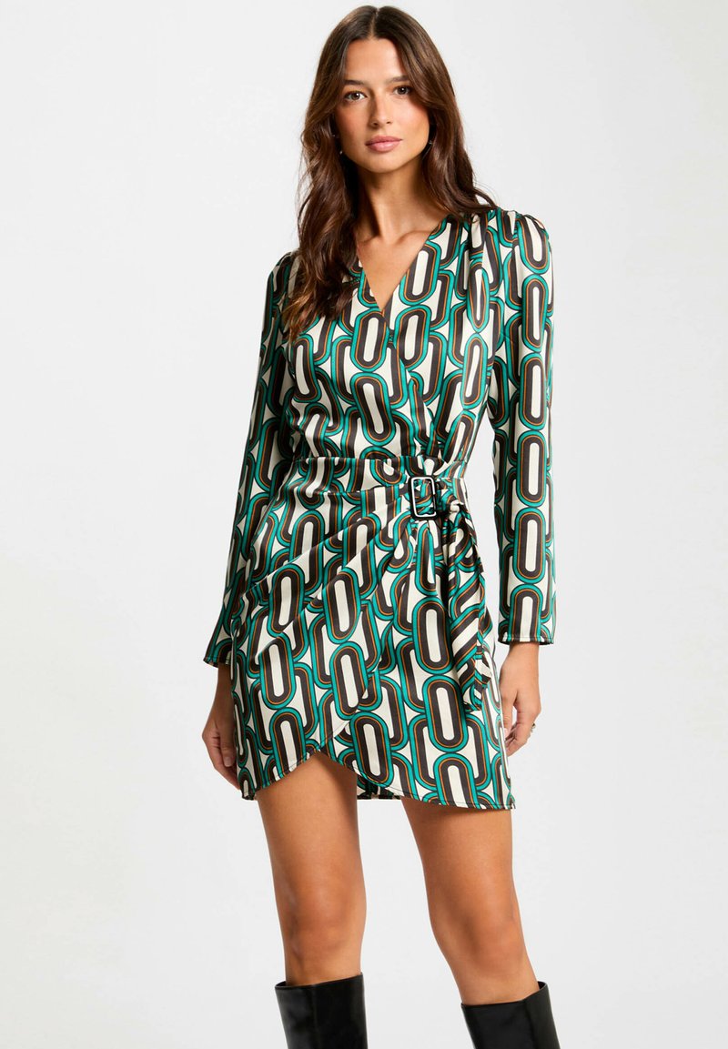 Robe portefeuille avec un motif géométrique en vert, noir et crème. Manches longues, décolleté en V et taille ceinturée avec un ourlet évasé.