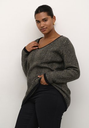 Black and beige herringbone-patterned knit sweater, V-neck design, long sleeves, ribbed cuffs and hem, paired with black pants.