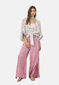 Kimono de tela ligera con estampado floral y mangas abiertas, combinado con pantalones satinados de pierna ancha en color rosa y un choker a juego.