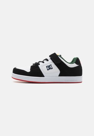 Baskets noir et blanc avec une tige en daim et cuir, comprenant une sangle et des lacets, doublure verte, semelle rouge et un logo sur le côté.