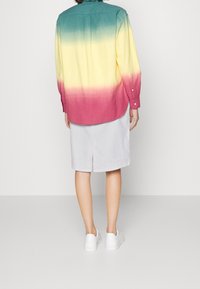 Värikäs napillinen paita liukuvärillä, joka vaihtuu sinivihreästä keltaiseen ja sieltä vaaleanpunaiseen. Yhdistetty harmaaseen hameeseen ja valkoisiin kenkiin.