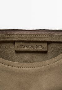 Zamszowy woreczek w oliwkowej zieleni o gładkiej fakturze. Posiada zamek błyskawiczny i wytłoczone logo "Massimo Dutti" na skórzanej naszywce.