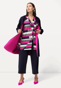 Färgglad randig blus i marinblått, rosa och grått; kombinerad med marinblå capribyxor; lager på lager med en klar rosa kappa och klara rosa klackar.