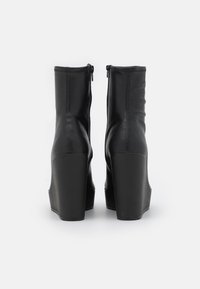 Black leather ankle boots with a high, chunky heel and a zip closure. Features a smooth texture and minimalistic design.