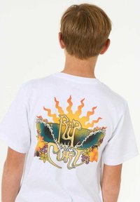 Weißes Baumwoll-T-Shirt mit einem bunten Druck auf der Rückseite, der stilisierte Wellen, Sonnenstrahlen und florale Akzente in verschiedenen Farben zeigt.