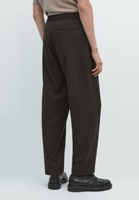 Pantaloni marroni dal taglio morbido con un tessuto testurizzato, vita elasticizzata e tasca posteriore, abbinati a scarpe nere con lacci.