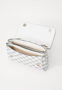 Borsa in ecopelle bianca con motivo trapuntato nero, hardware dorato e chiusura a scatto magnetica. Presenta due scomparti interni.