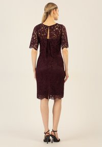 Bordeauxfarbenes Spitzenkleid mit kurzen Ärmeln, einem Schlüsselloch-Rücken und knielangem Schnitt, mit gewelltem Saum und aufwendigen floralen Mustern.