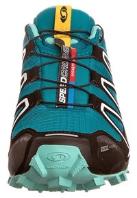 Turkos och svart löparsko med texturerad ovandel, symmetriskt snörningssystem, tydlig logotyp och robust sula utformad för grepp.