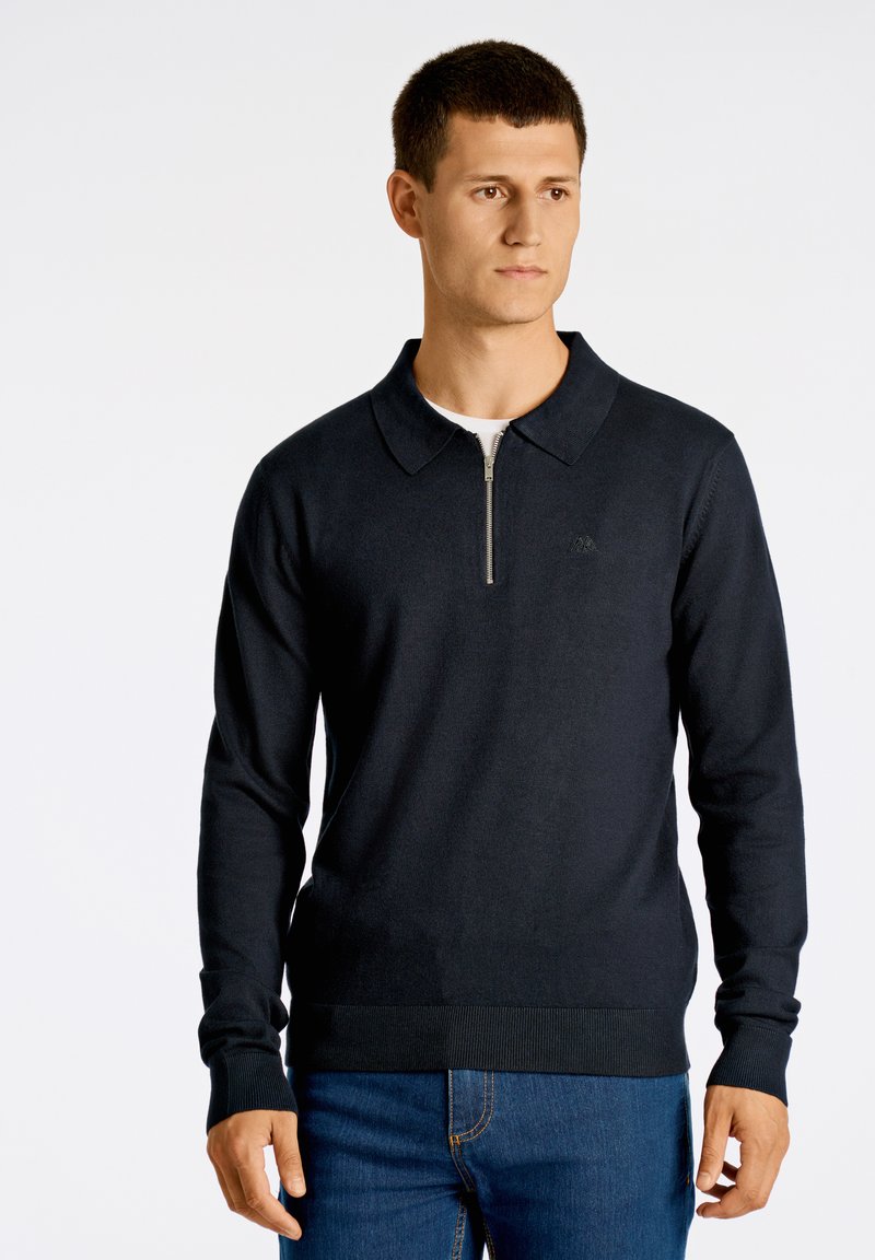 Marinblå tröja med dragkedja i kragen, långa ärmar och ribbade muddar och fåll; tillverkad av mjukt material med en subtil logotypdetalj.