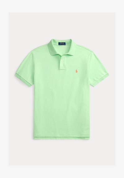 Polo en coton vert clair avec col classique, manches courtes et petit logo brodé orange sur la poitrine gauche.