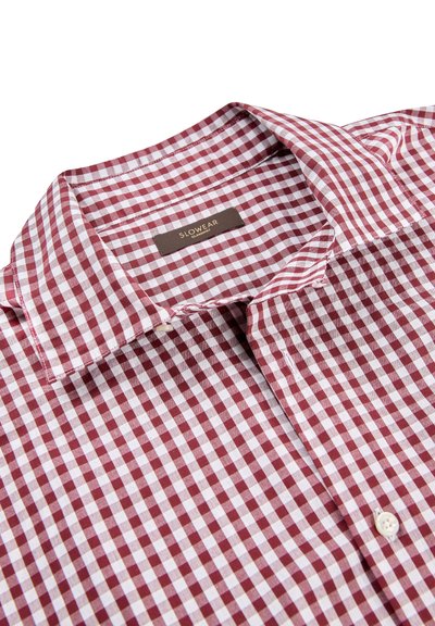 Chemise à carreaux bordeaux et blanche, dotée d'un col boutonné, de boutons unis et d'un tissu doux et texturé. L'étiquette indique le nom de la marque.