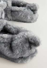 Pantofole in pelliccia sintetica grigia con una texture morbida, forma arrotondata e design aperto sulla punta. Presentano un rivestimento morbido e bordi leggermente sollevati.