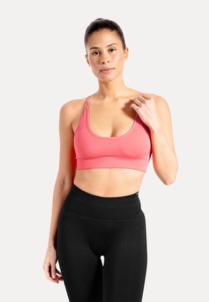 Reggiseno sportivo rosa con scollo a U e spalline regolabili, abbinato a leggings neri a vita alta, realizzati in tessuto liscio ed elastico.