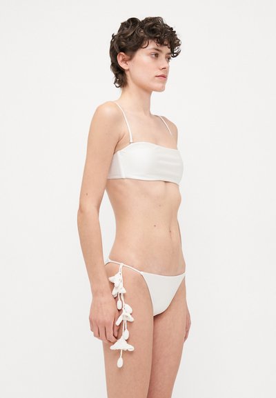 Hvid bikini sæt med en bandeau top med tynde stropper og en lavtsiddende underdel prydet med tekstureret dekorativt trim på den ene side.