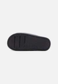 Suela de zapato de goma negra con una superficie texturizada que presenta surcos y un patrón geométrico para ofrecer tracción, tacón redondeado y bordes limpios.