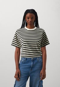 T-shirt noir et blanc à rayures avec un col rond et des manches courtes, en coton doux. Associé à un jean taille haute bleu.