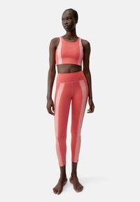 Sportieve set met een koraalkleurige crop top met contrasterende strepen en bijpassende high-waisted legging, gemaakt van een zachte, stretchy stof.