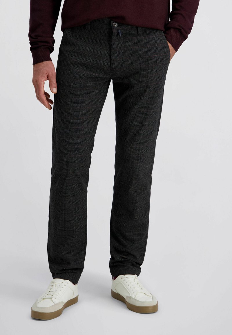 Donkergrijze geruite broek gemaakt van een gestructureerde stof, met een knoopsluiting, twee zijzakken en gecombineerd met witte sneakers.