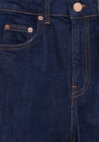 Jeans de mezclilla azul oscuro con remaches de cobre, costuras naranjas, un bolsillo delantero y diseño clásico de cinco bolsillos. Textura suave.