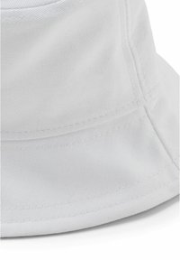 White cotton bucket hat with ribbed texture, horizontal stitching details along the brim, featuring a soft and flexible design.