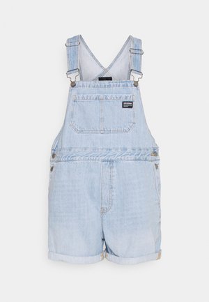 Peto vaquero azul claro con un corte holgado, con tirantes ajustables, bolsillo frontal y pantalones cortos remangados. Tejido texturizado con un acabado desgastado.