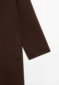 Brauner Wollmantel mit entspannter Passform, geraden Ärmeln und einer unauffälligen Seitentasche für ein minimalistisches Design.