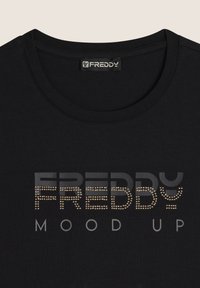 Maglietta nera con scollatura tonda, logo "FREDDY" in strass grigi e dorati, e il testo "MOOD UP" sotto. Tessuto dalla superficie liscia.