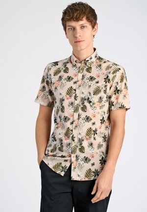 Kortærmet skjorte i lys beige bomuldsstof, med livlige grønne og blomster mønstre, samt en frontlomme. Design med knap-ned krave.