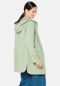 Mintgroene hooded jacket van lichtgewicht stof, met een ritssluiting en drukknoopsluiting, zijzakken en een langere achterkant.