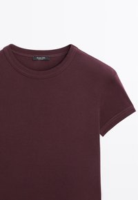 T-shirt a maniche corte color bordeaux scuro con collo a giro e cuciture visibili, dotato di un'etichetta nera Massimo Dutti all'interno del collo.