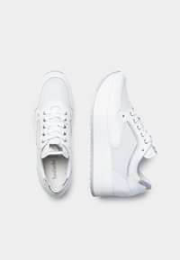 Sneaker bianchi con parte superiore in rete, chiusura con laccetti, colletto imbottito e suola in gomma spessa. Accenti argentati includono occhielli e dettagli del logo.