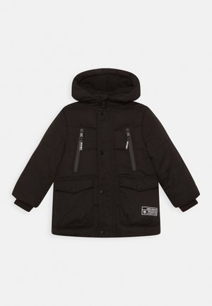 Schwarze gesteppte Jacke mit Kapuze, ausgestattet mit zwei Reißverschlusstaschen und zwei Taschen mit Knopfklappe. Gerippte Bündchen und ein Markenlabel an der Seite.