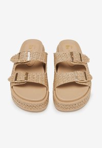 Sandali platform beige con cinturini intrecciati simili alla paglia, doppie fibbie regolabili e una soletta in plastica liscia. Suola texture per maggiore aderenza.