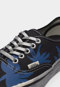 Μαύρο αθλητικό παπούτσι Vans με μπλε σχέδια φύλλων, ασημί γκλίτερ κορδόνια, λευκά ράμματα και λευκή λαστιχένια σόλα.