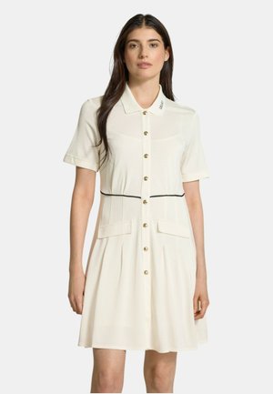 Vestito crema a maniche corte con chiusura frontale a bottoni, colletto, cintura nera in vita e due tasche frontali. Include bottoni dorati e gonna plissettata.