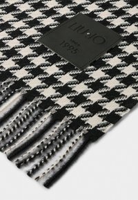 Sciarpa a motivo houndstooth in bianco e nero con bordi sfrangiati, dotata di un'etichetta in pelle nera impressa con "LIU JO dal 1995".