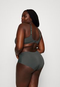 Dark green bra and high-waisted briefs made from smooth fabric with mesh accents. Adjustable straps and hook closure on the bra.