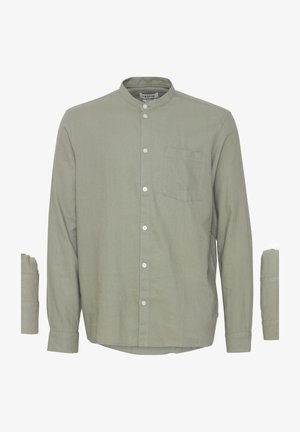 Lysegrøn olivengrøn langærmet skjorte med mandarinkrave, knapper foran og brystlomme, vist på hvid baggrund.