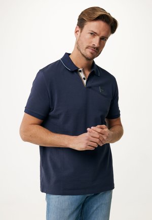 Camiseta tipo polo en color marino con cuello, que presenta una tapeta interior a rayas y un pequeño logo en el pecho. Tejido cómodo, mangas cortas.