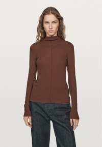 Brown turtleneck top made of soft fabric, featuring a fitted silhouette and long sleeves with a slight flare at the cuffs. No visible patterns.
