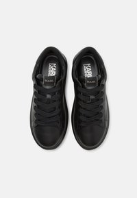 Sneaker in pelle nera con punta rotonda, superficie texturizzata e lacci a contrasto. Presenta il logo all'interno e un design classico.