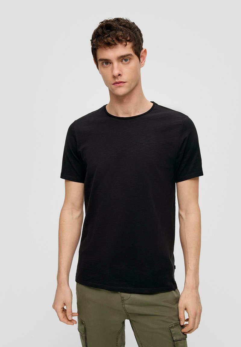 Musta crew-neck t-paita, joka on valmistettu kevyestä kankaasta. Lyhyet hihat, sileä pinta, istuva muoto ja huomaamaton kanttaus kaula-aukon ympärillä.