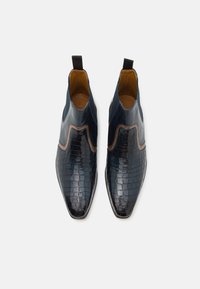 Cizme de gleznă din piele bleu întunecat, cu un model lucios de crocodil, accente maro contrastante, vârf ascuțit și tab-uri pentru o încălțare ușoară.