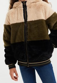 Fuzzy zip-up jacka med en färgblockdesign i beige, olivgrön och svart. Inkluderar huva och randiga ribbade ärmslut och nederkant.