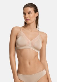 Reggiseno wireless beige con dettagli in pizzo trasparente sui coppe, spalline regolabili e banda liscia. Tessuto morbido e forma triangolare.