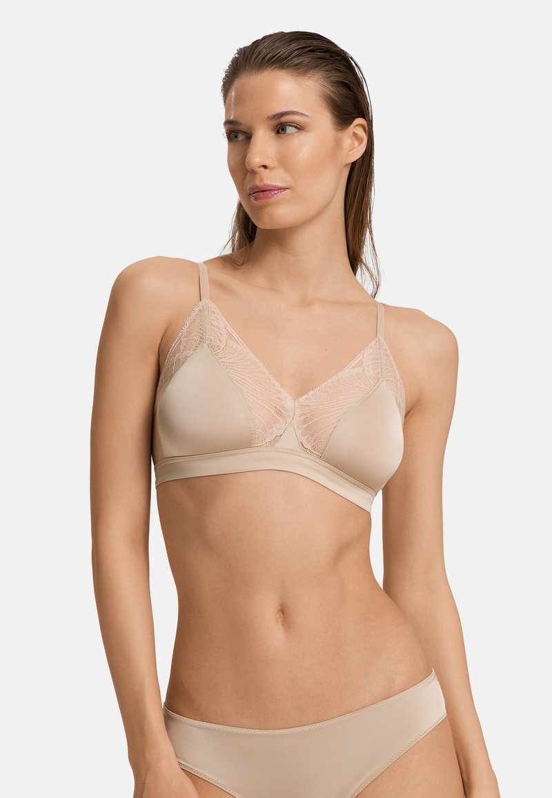 Reggiseno wireless beige con dettagli in pizzo trasparente sui coppe, spalline regolabili e banda liscia. Tessuto morbido e forma triangolare.