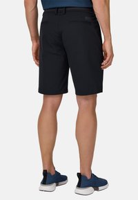 Pantaloncini neri realizzati in tessuto leggero, con parte anteriore piatta, due tasche posteriori e vestibilità comoda. Abbinati a scarpe sportive blu.