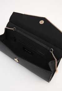 Borsa a pochette nera con finitura testurizzata, hardware dorato e tasca interna con zip. Tracolla in catena attaccata per il trasporto.